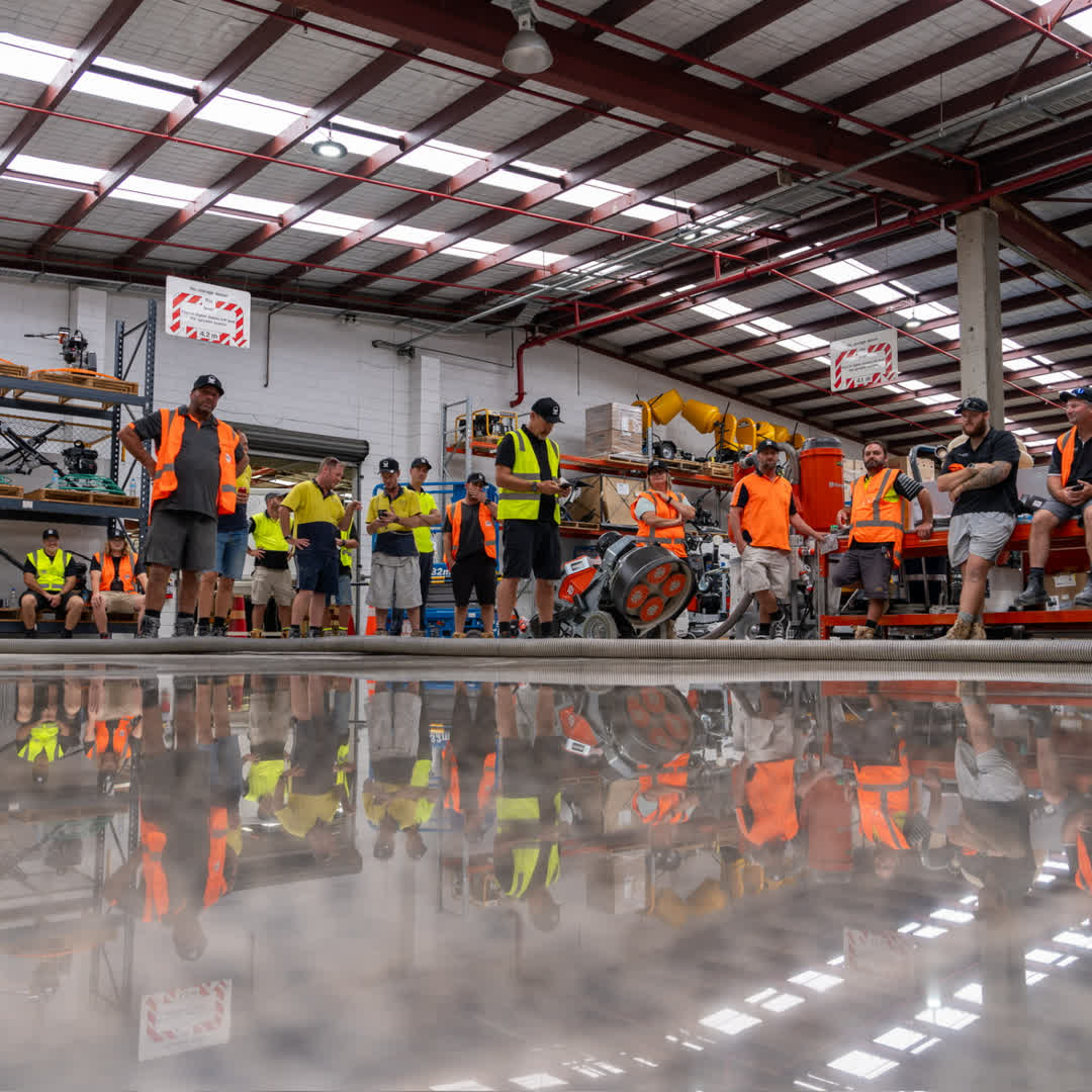 Course participants gathered inside the training warehouse beside a polished concrete floor